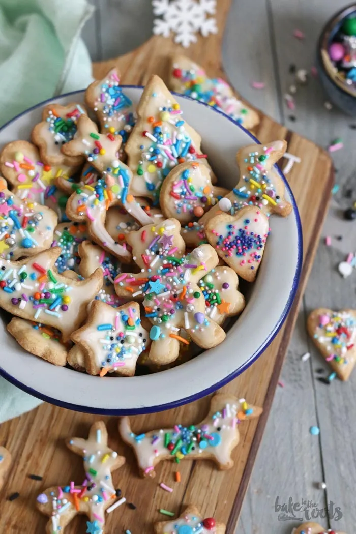 Bunte Ausstecherle mit Zuckerguss und Streuseln, frisch gebacken auf einem Kuchengitter