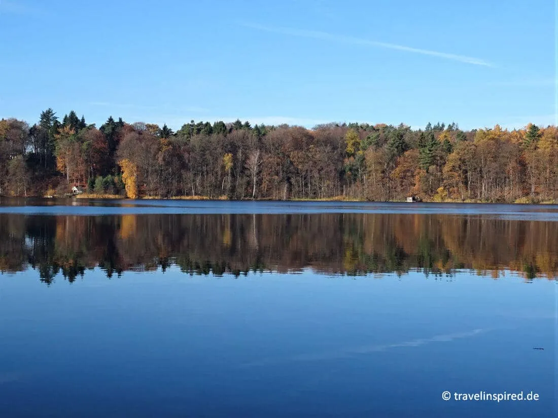 Bunte Herbstspiegelungen am idyllischen Großensee in der Stormarnschen Schweiz, ein malerisches Ziel für Natur-Unternehmungen.