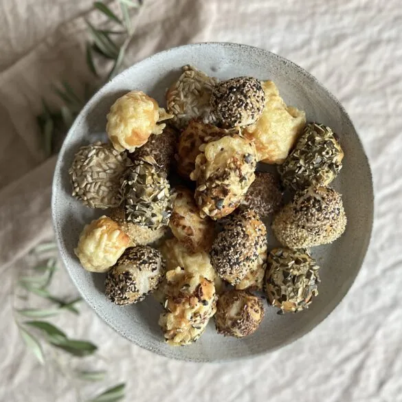 Bunte Partybrötchen mit Röstzwiebeln, Käse, Kürbiskernen und Sesam auf einem Backblech