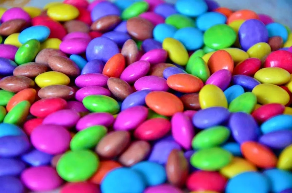 Bunte Smarties werden kunstvoll auf der Oberfläche der Regenbogentorte arrangiert, um ein lebendiges Muster zu erzeugen