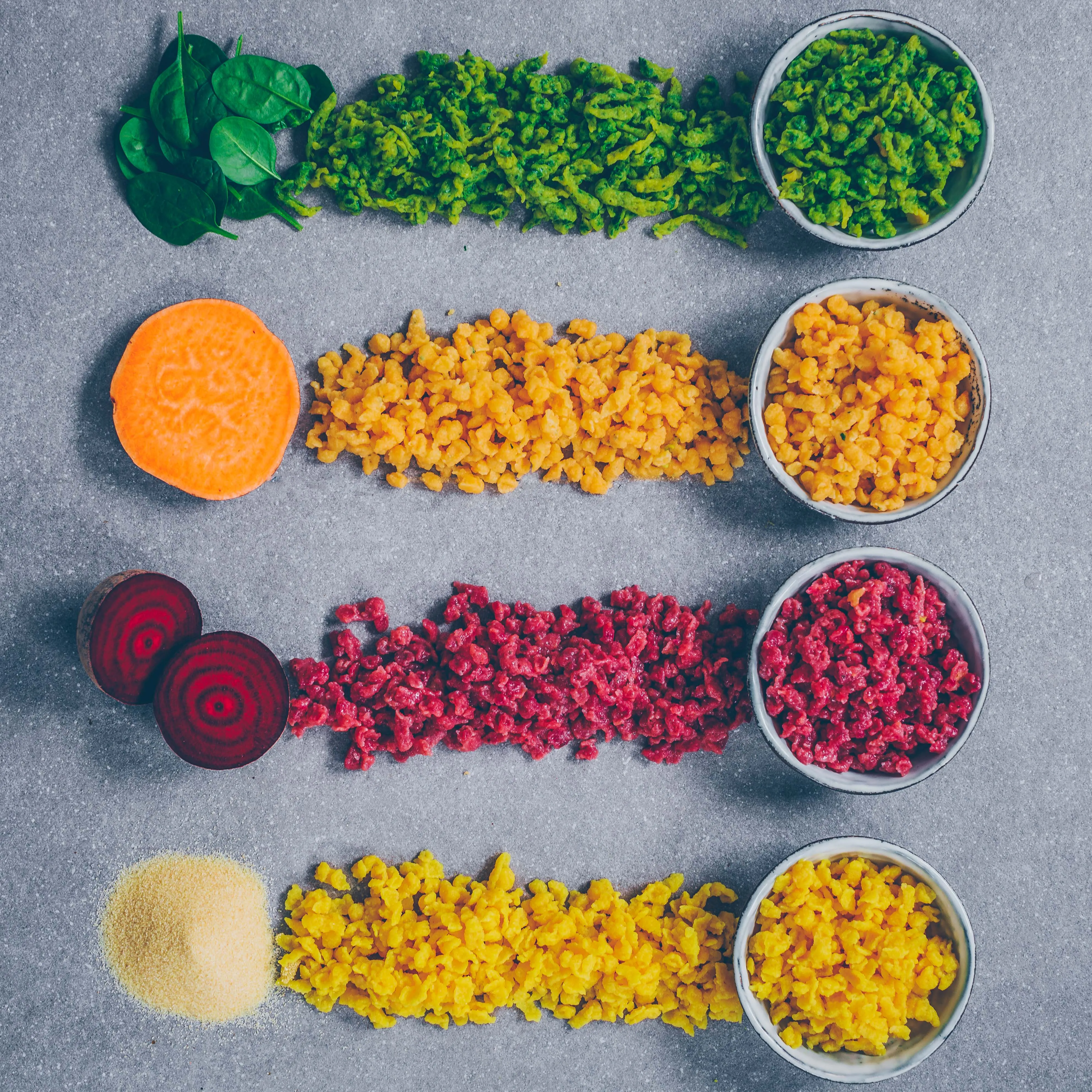 Bunte vegane Knöpfli und Spätzle mit Kurkuma, Spinat, Süßkartoffel und Rote Bete auf einem Teller angerichtet.