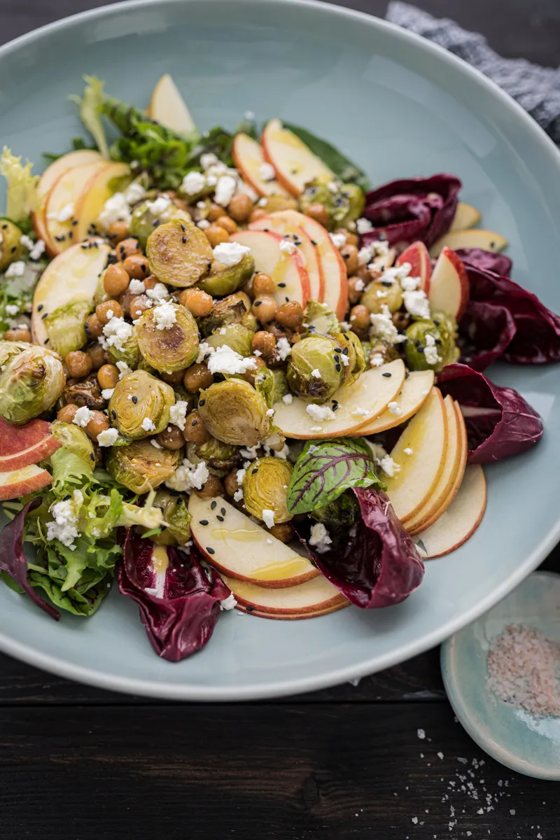 Bunter Rosenkohl Salat mit Apfel, Kichererbsen und Feta in einer Schale mit orientalischem Dressing