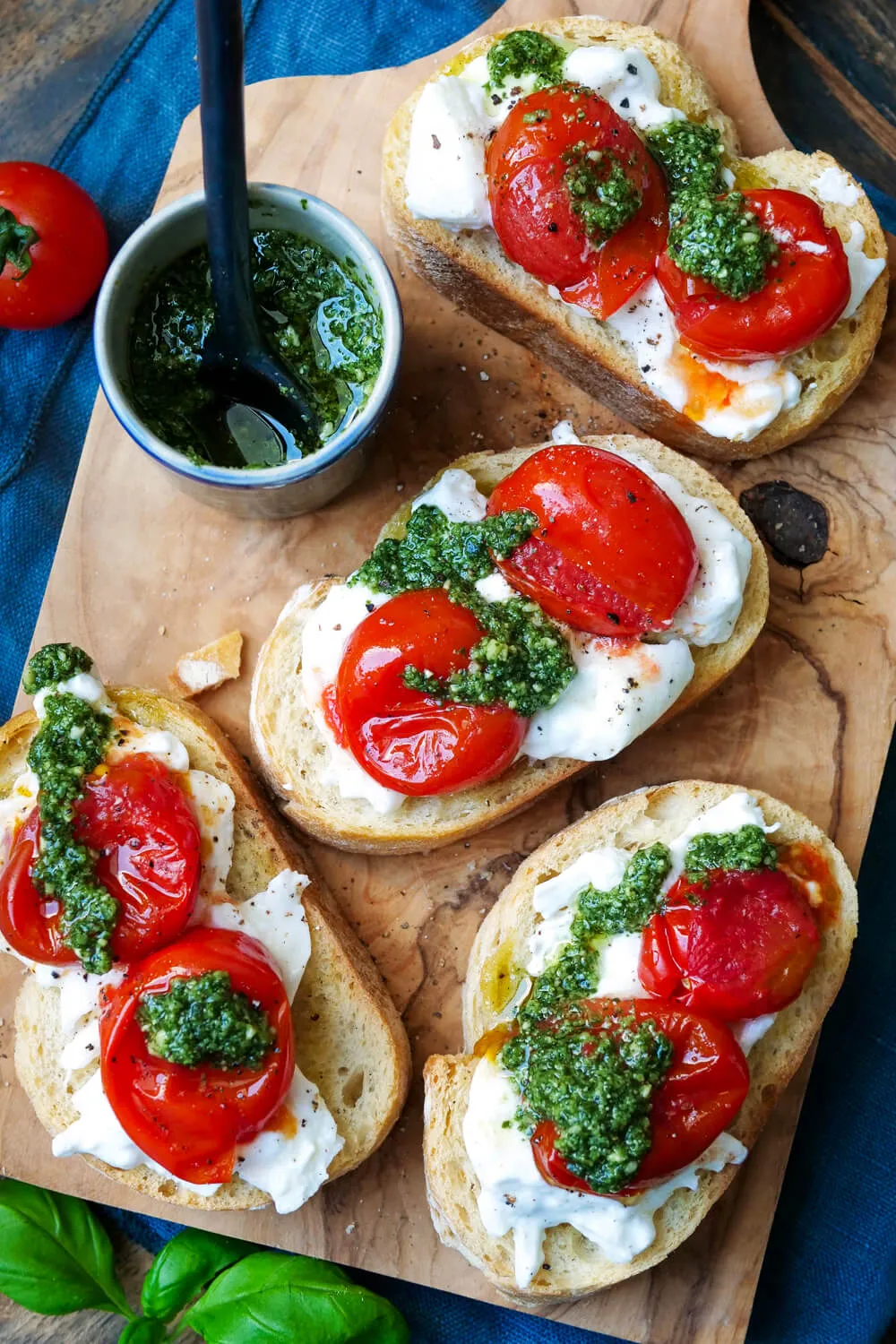Burrata-Bruschetta mit Pesto auf einem Holzbrett.