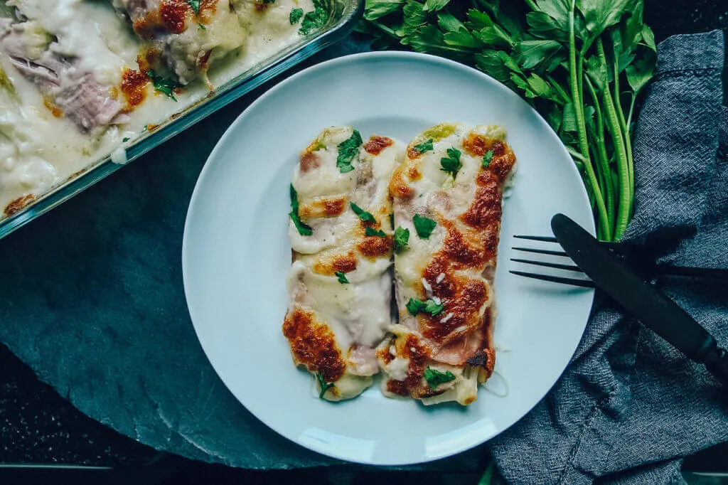 Chicoree mit Schinken umwickelt, kunstvoll in der Auflaufform arrangiert.
