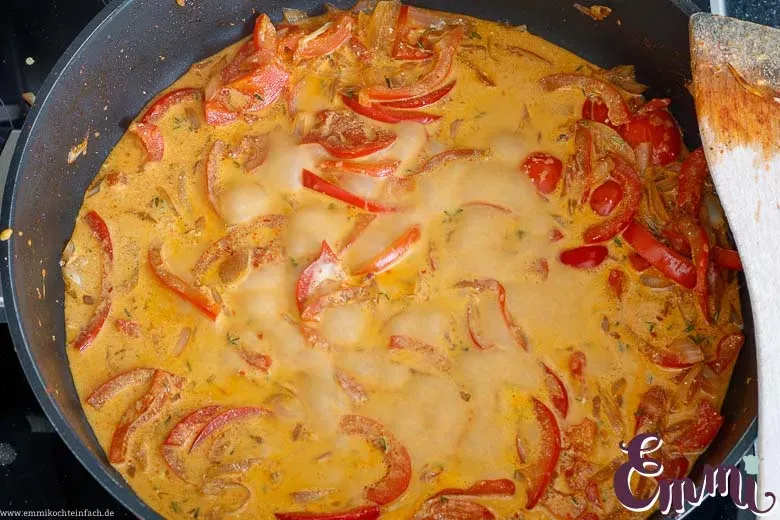Cremige Paprika-Rahmsoße köchelt in der Pfanne, verfeinert mit Geflügelfond und Crème fraîche