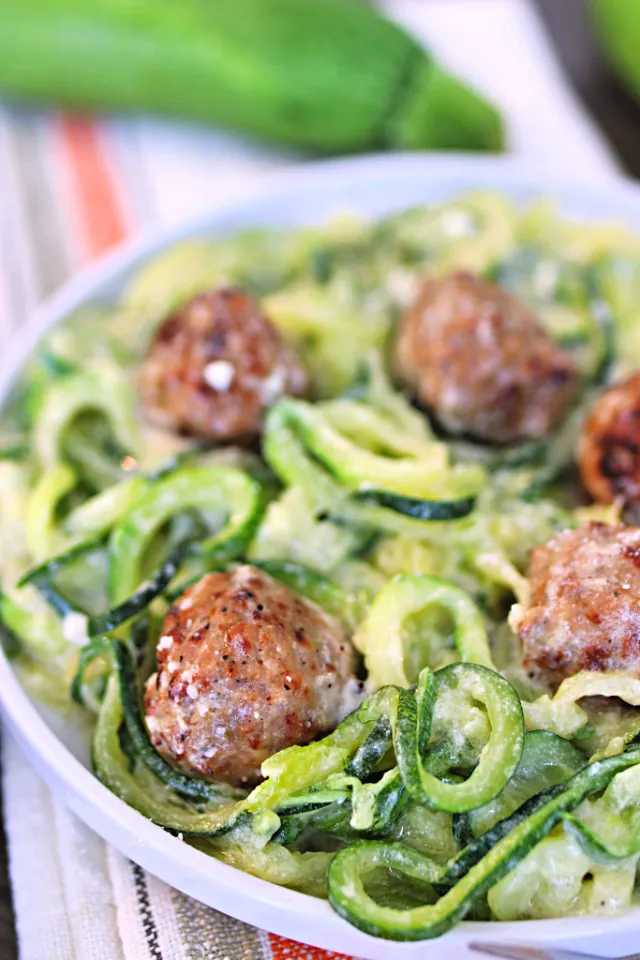 Cremige Zucchini Nudeln Alfredo mit Hähnchen-Hackbällchen auf einem Teller.