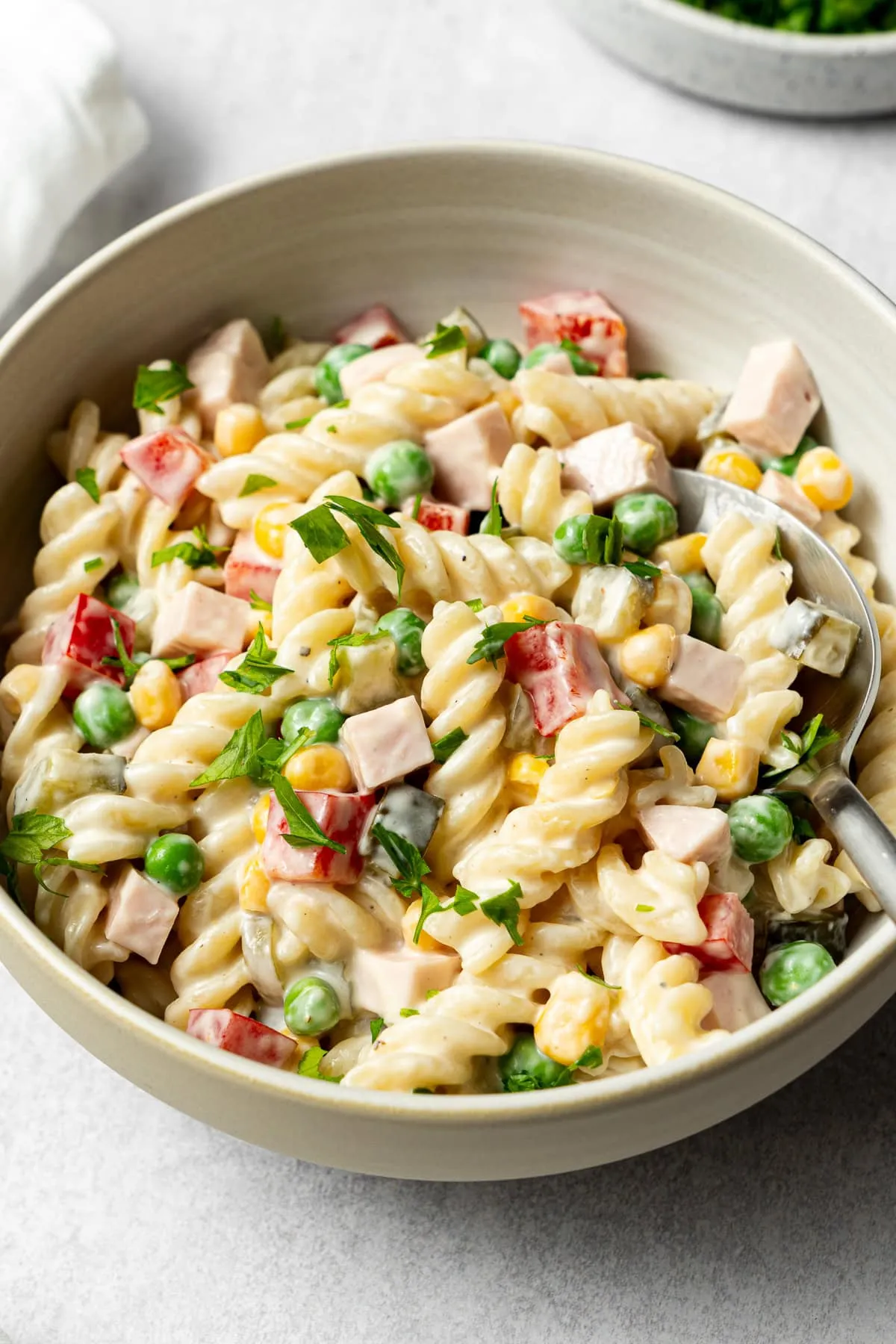 cremiger deutscher Nudelsalat mit Petersilie garniert in einer Schüssel mit Löffel