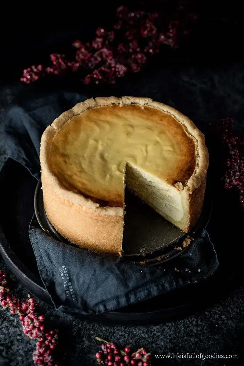 Cremiger Käsekuchen angeschnitten, goldbraun gebacken auf Tortenplatte