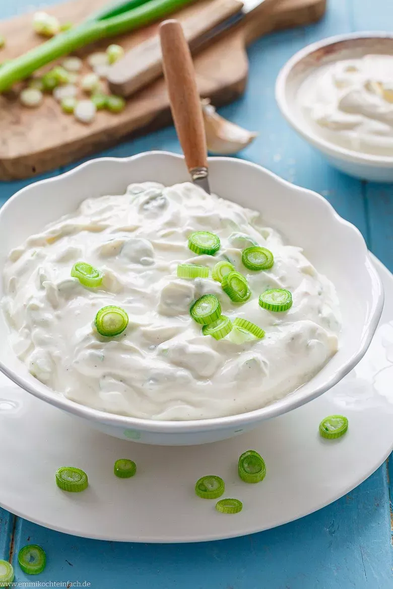 Cremiger Sour Cream Dip in einer Schale, garniert mit frischen Frühlingszwiebeln, perfekt zum Grillen und Dippen.