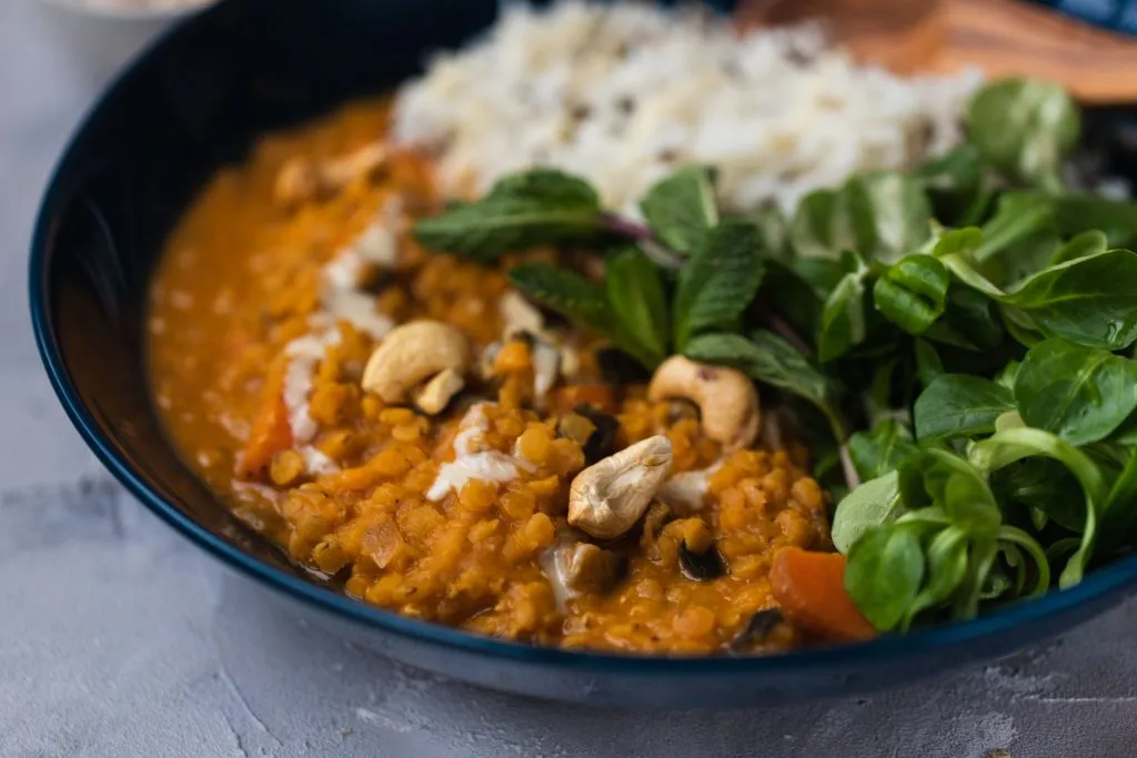 Cremiges Kokos-Linsen-Curry köchelt im Topf, ein schnelles Curry Reis Rezept.