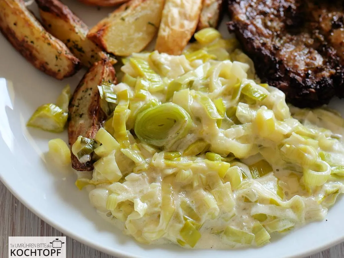 Cremiges Lauchgemüse, serviert mit goldbraunen Wedges und einem saftigen Nackensteak auf einem modernen Teller.