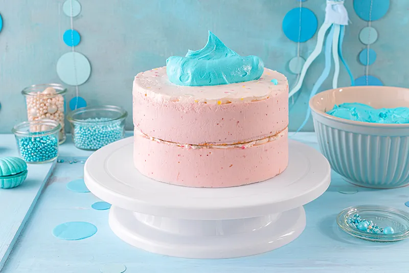 Das Auftragen der vorbereiteten türkisen Schlagcreme auf die Oberfläche der gestapelten Torten, der erste Schritt zur ozeanischen Optik.