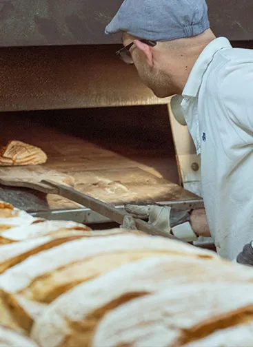 Das Innere einer traditionellen Bäckerei mit Öfen, in denen Bäcker Produkte frisch gebacken werden.
