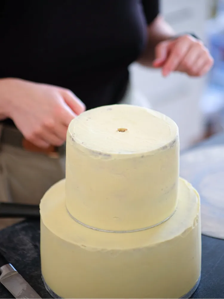 Das letzte Stück des Tortendübels wird mit einem Holzstück als Verlängerung in die Torte gedrückt