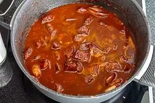 Das Rindergulasch schmort langsam und sanft im Bräter, wodurch das Fleisch zart wird und die Soße sich bindet.