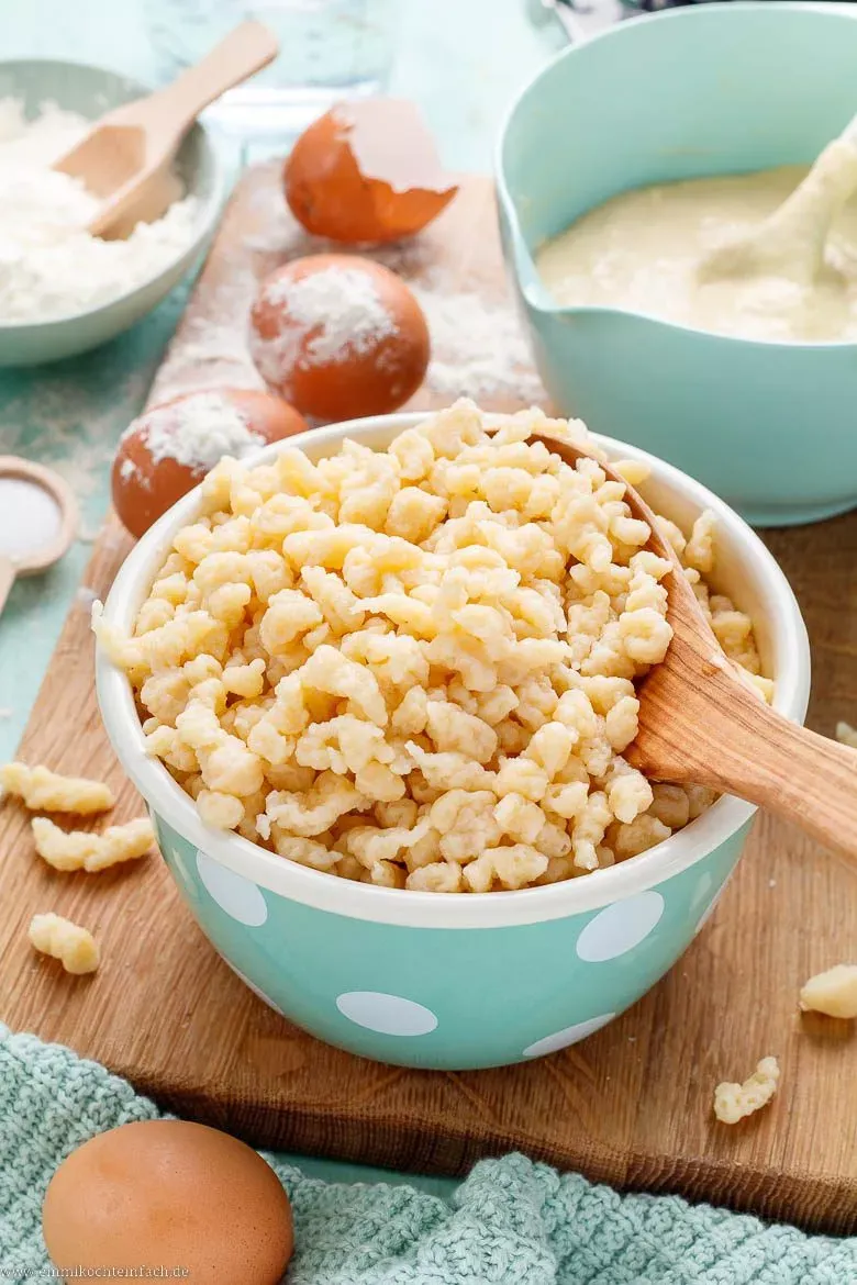 Das Spätzle Rezept Schritt für Schritt: Frischer Spätzleteig wird mit einem Spätzlehobel direkt ins kochende Salzwasser gegeben, um Knöpfle zu formen.