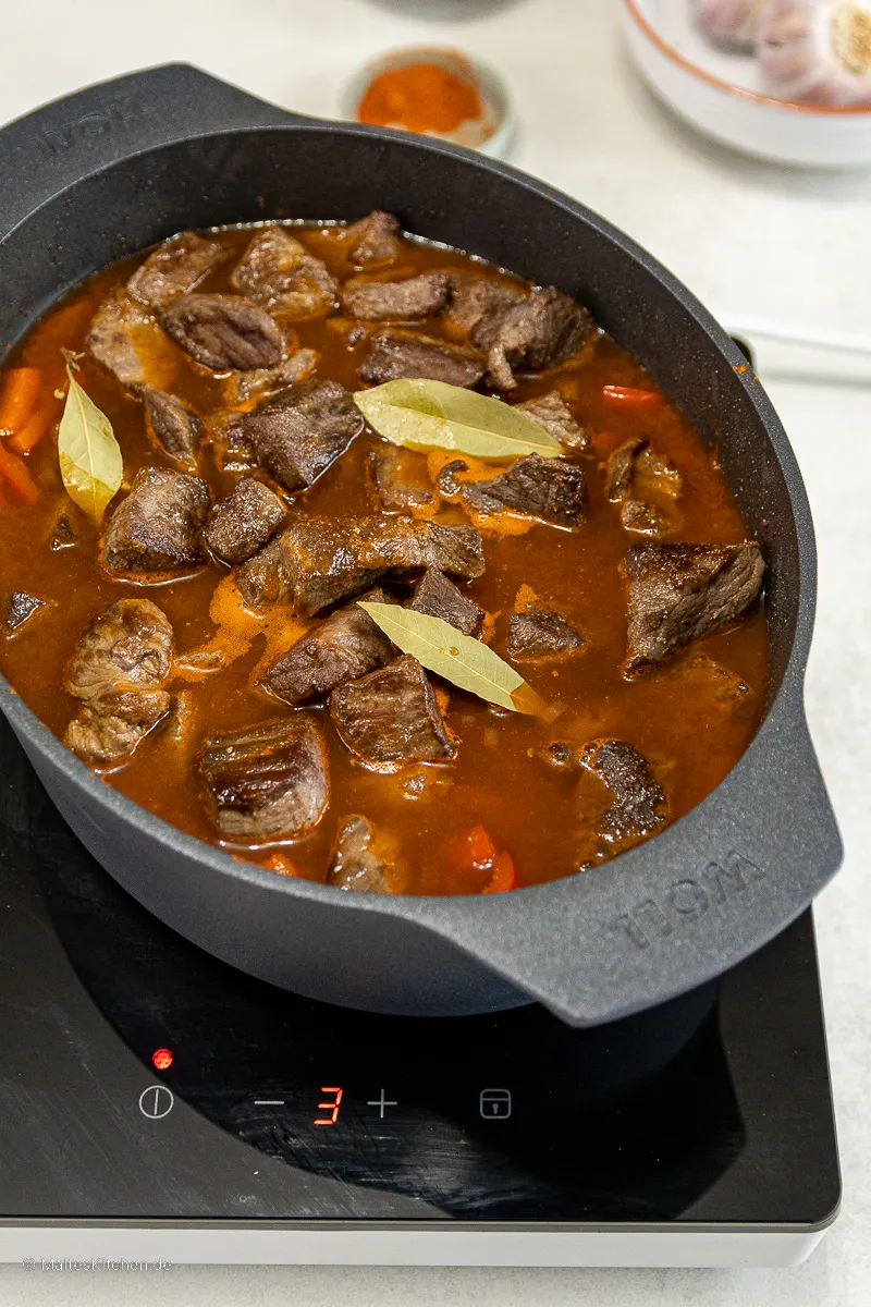 Das ungarische Gulasch schmort langsam im Bräter, um seine volle Geschmacksentwicklung zu entfalten.