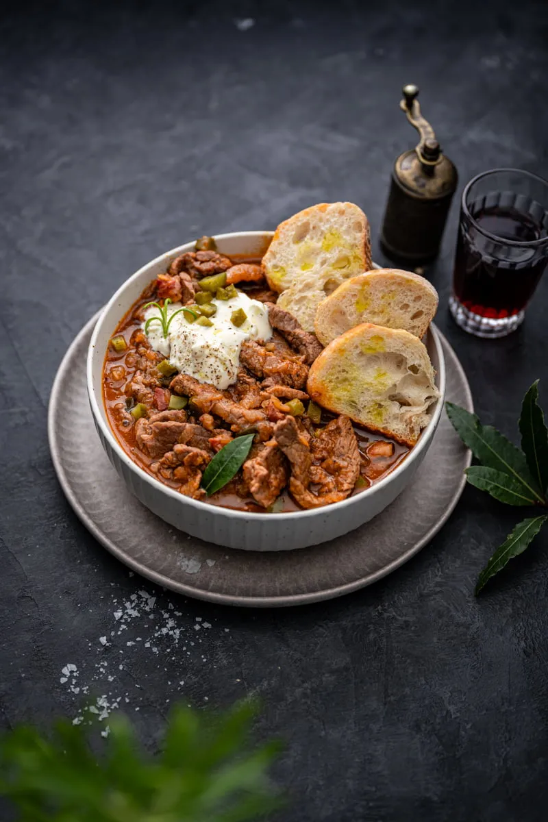 Deftiger Rouladentopf mit Fleisch und Soße, garniert mit frischen Kräutern in einer Schüssel