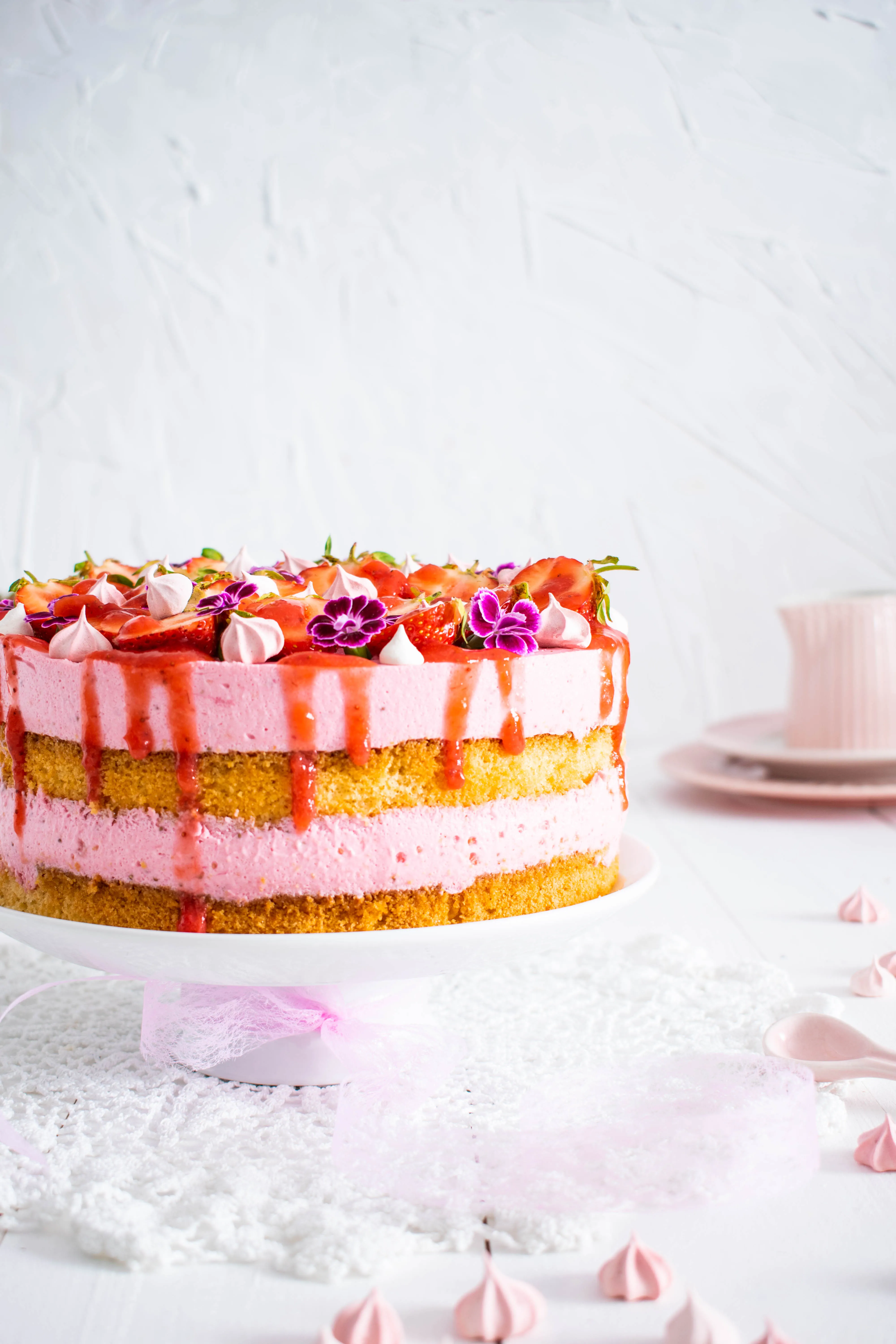 Dekorierte Erdbeersahnetorte mit frischen Erdbeeren und Baiser auf weißem Teller