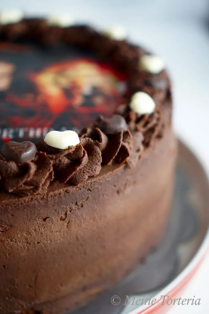 Dekorierte Schokoladen-Karamell-Geburtstagstorte mit essbarem Logo und Schokoladenverzierungen