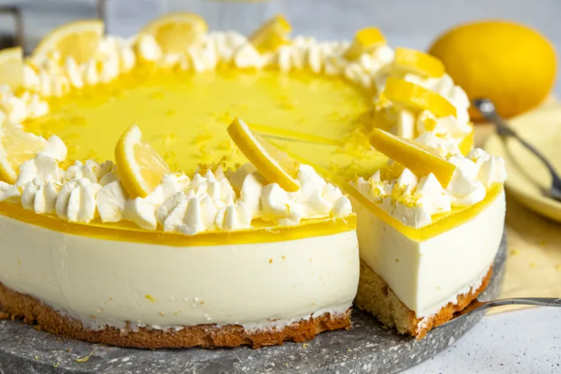 Dekorierte Zitronen-Joghurt-Sahne-Torte mit Sahnetuffs und frischen Zitronenscheiben