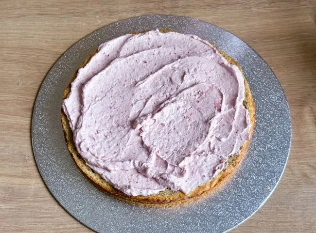 Der abgekühlte Kuchenboden wird für die Füllung halbiert und mit etwas Creme bestrichen.