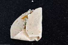 Der Faltvorgang eines Wraps: Unterer Teil hochgeklappt, rechte Seite eingefaltet