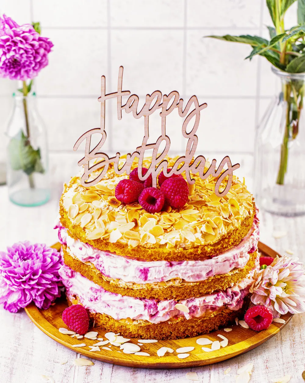 Der fertige Himbeer-Quark Naked Cake, dekoriert mit frischen Himbeeren und einem Cake Topper