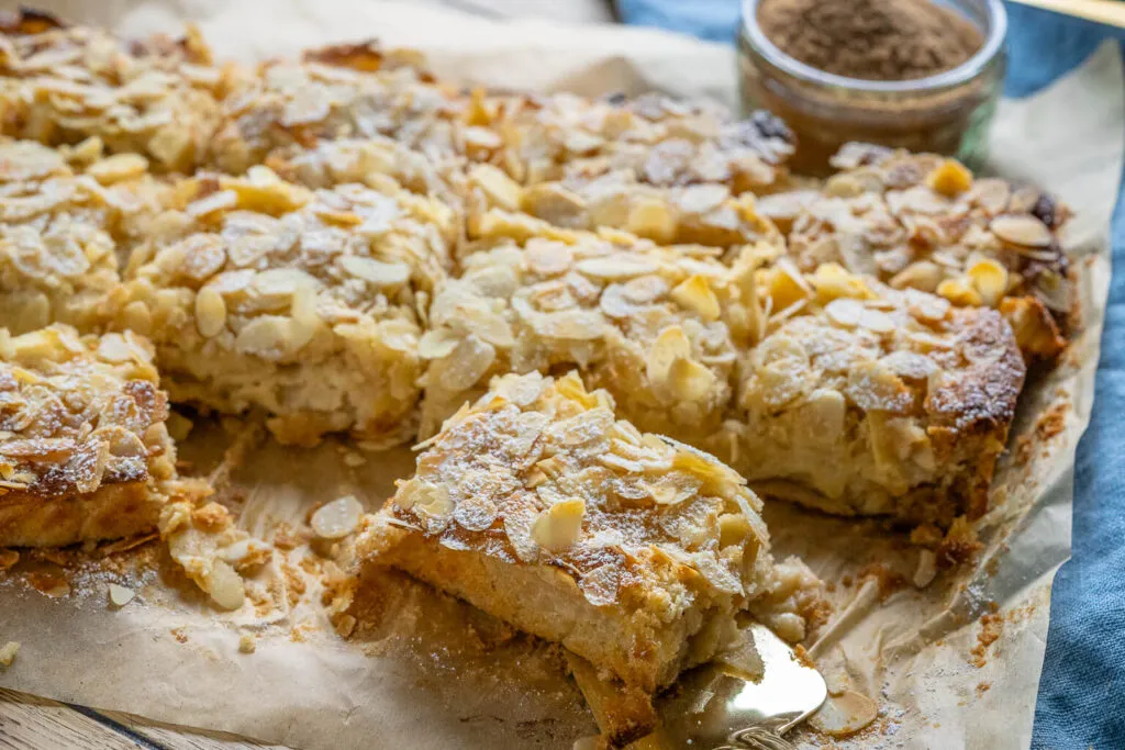 Der köstliche Apfelkuchen mit Marzipan in einer Backform, bereit zum Anschneiden, symbolisiert gemütliche Herbst- und Weihnachtsstimmung