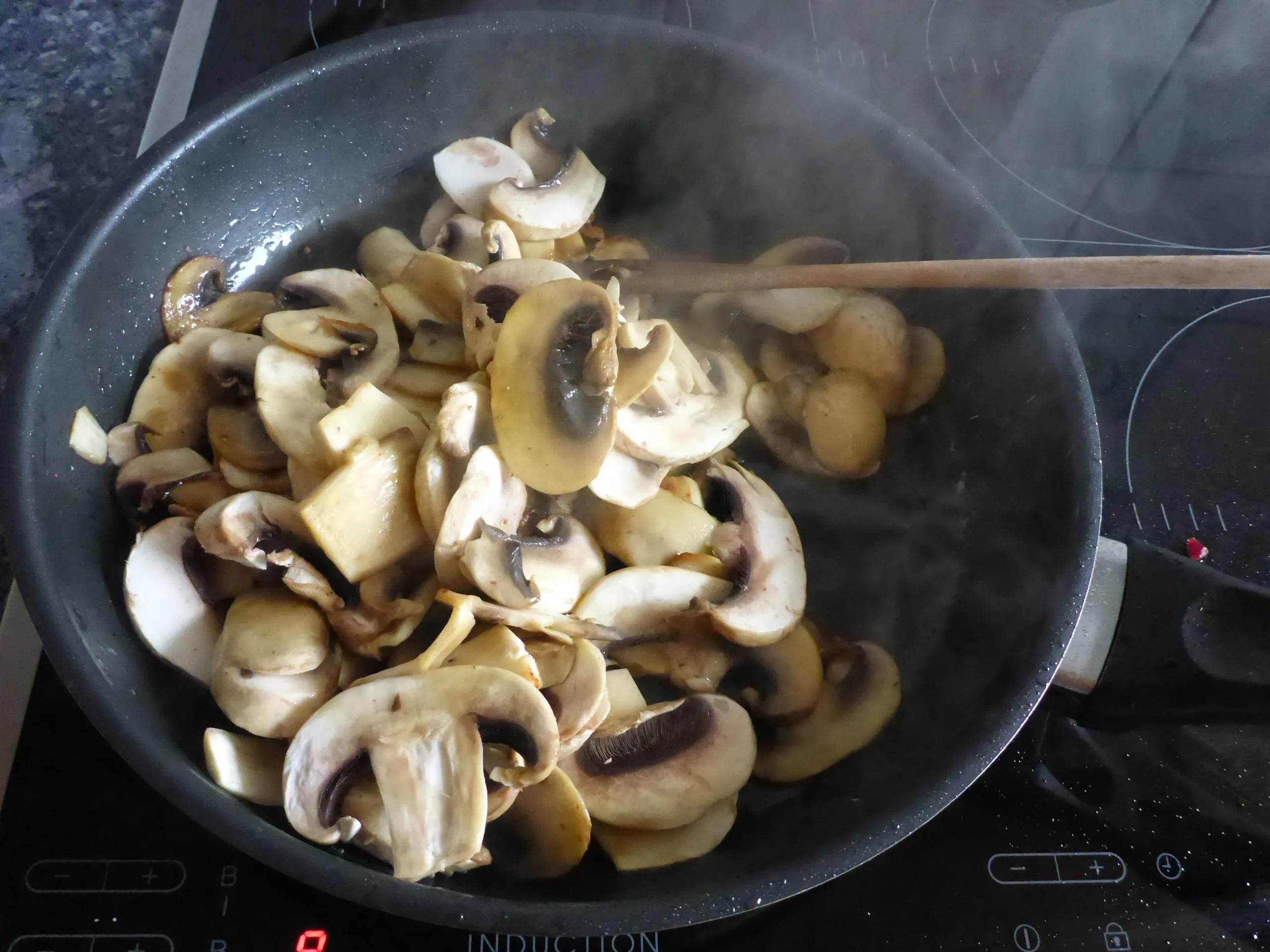 Der Moment, in dem Speisestärke über die angebratenen Pilze gestreut wird, um die cremige Konsistenz der Lauch-Pilz-Rahmsauce für die Schnitzelpfanne zu binden.