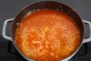 Der Reis köchelt mit Fond und Safranfäden in der Pfanne