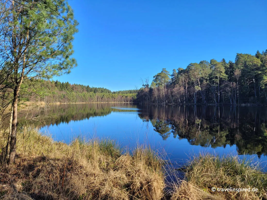 Der ruhige Schwarzsee im Naturschutzgebiet Hellbachtal, ein abgeschiedener Ort für entspannte Unternehmungen und Naturgenuss in Schleswig-Holstein.