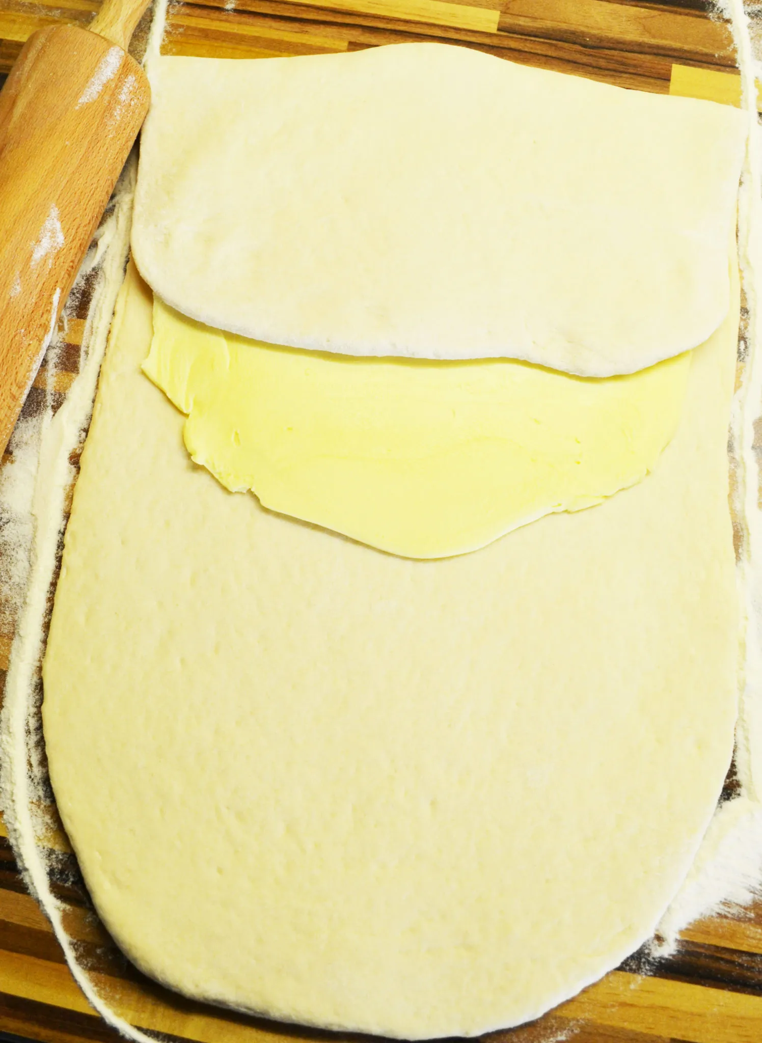 Der Teig wird sorgfältig gefaltet, um die Butterschichten für Blätterteig-Brötchen einzuschließen.