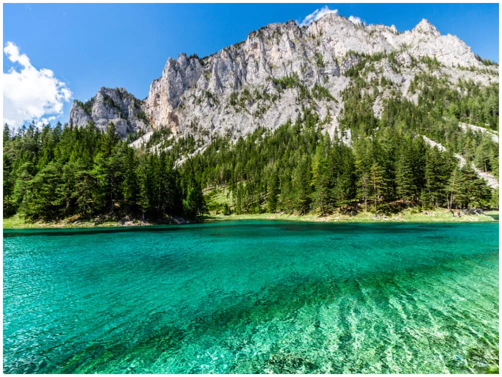 Der türkisblaue Grüne See in der Steiermark, umgeben von Wäldern und Bergen, ideal für Wanderungen im Juli