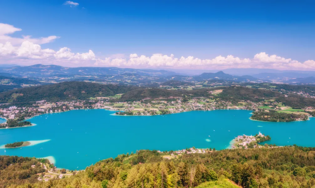 Der türkisblaue Wörthersee mit einem Schloss am Ufer in Kärnten, Österreich, perfekt für einen entspannten Aktivurlaub im September