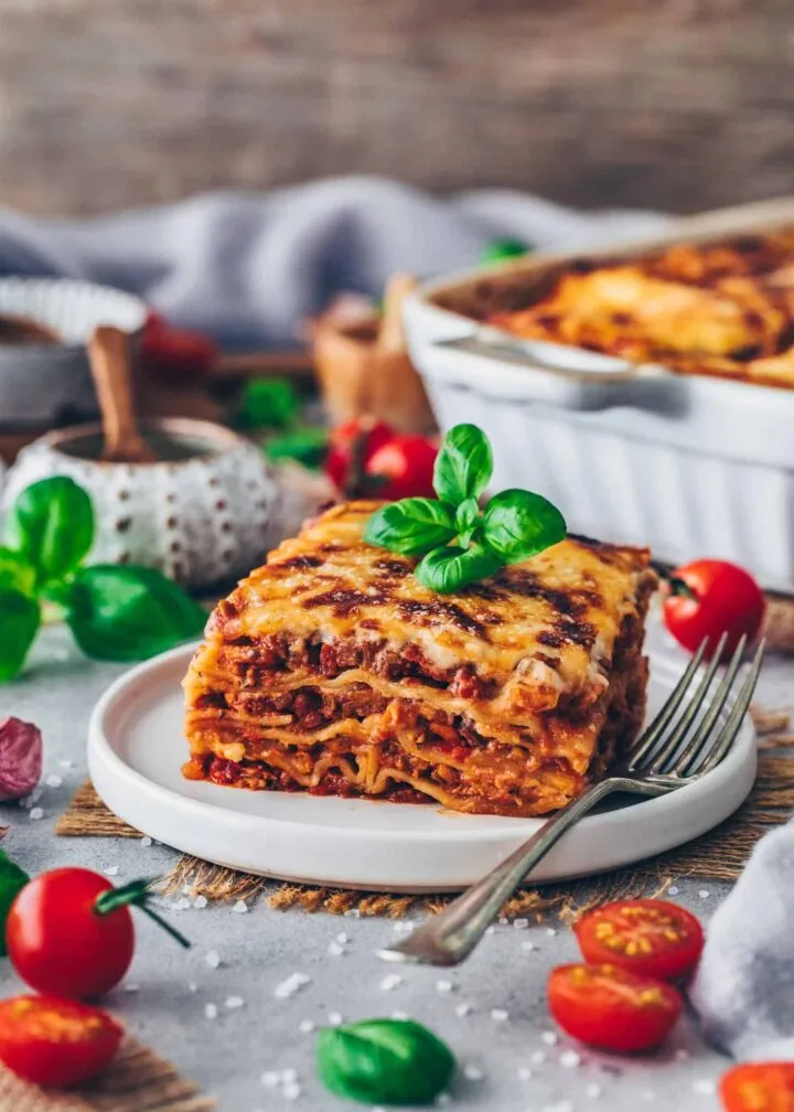 Detailansicht einer frisch geschnittenen Scheibe veganer Lasagne, die die geschichteten Nudeln, Bolognese und Béchamelsauce zeigt.