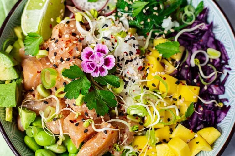 Detailaufnahme einer gesunden Poké Bowl mit frischen Zutaten wie mariniertem Lachs und knackigem Rotkohl