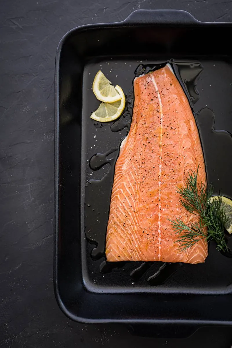 Detailaufnahme eines Tellers mit Kartoffelsalat, garniert mit Lachs, der die Textur des zerzupften Lachses und die Kruste der Quetschkartoffeln hervorhebt.