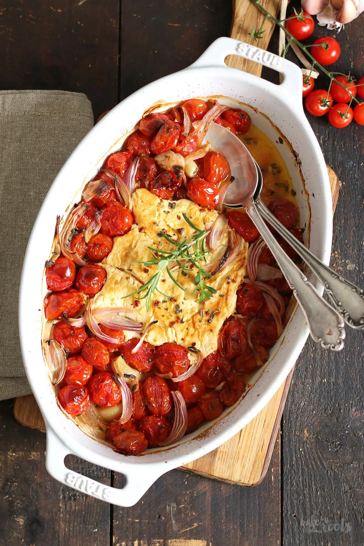 Detaillierte Ansicht der vorbereiteten Ofen-Feta-Pasta Zutaten in der Auflaufform vor dem Backen, mit Olivenöl beträufelt.