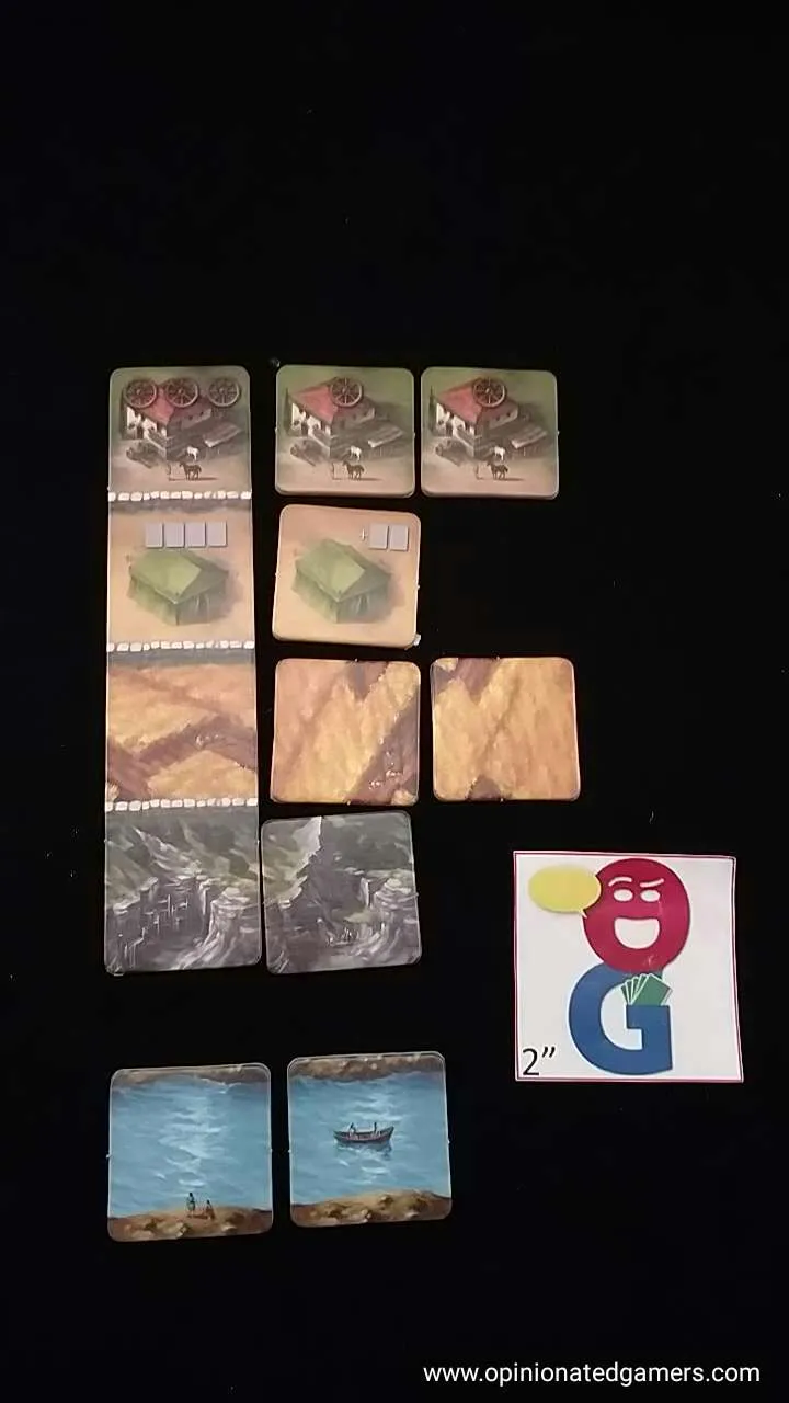 Detaillierte Ansicht von Brettspielkarten mit verschiedenen Ressourcen und einer Holzkonstruktion in Form eines Kolosseums.