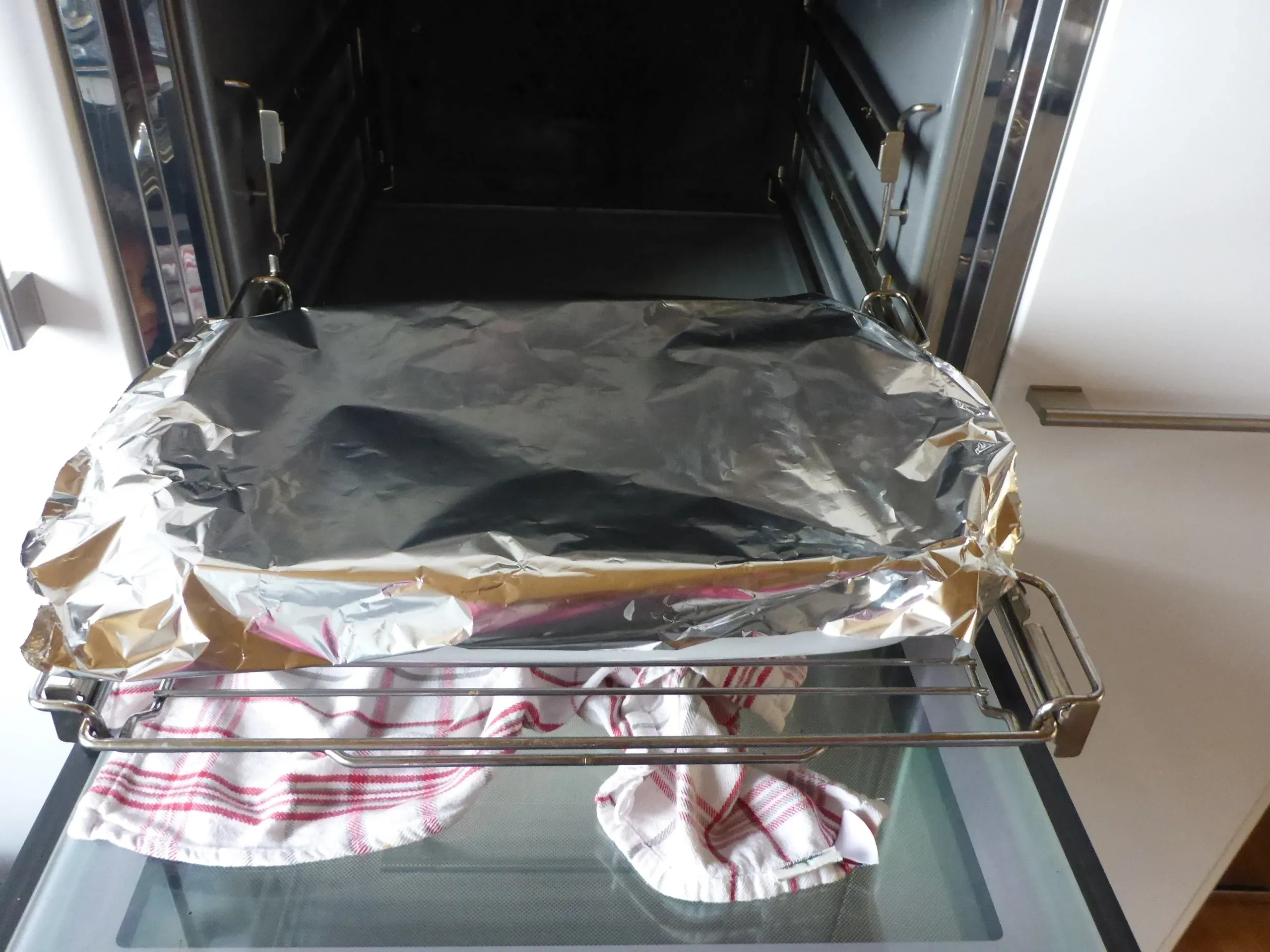 Die Auflaufform mit der Schnitzelpfanne wird sorgfältig mit Aluminiumfolie abgedeckt, um das Fleisch zart zu halten und die Aromen während des Backens zu versiegeln.