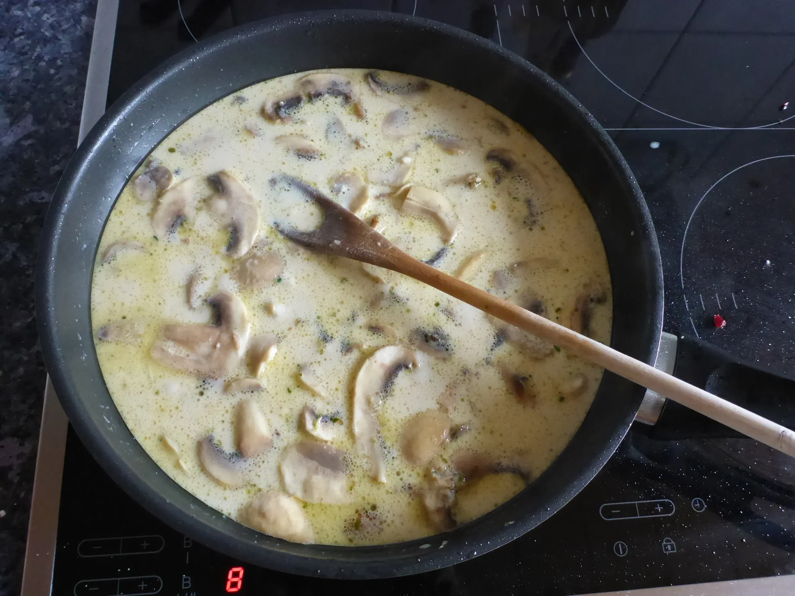 Die cremige Lauch-Pilz-Speck-Sauce köchelt in der Pfanne, entwickelt ihren vollen Geschmack, bevor sie über das Fleisch der Schnitzelpfanne gegossen wird.