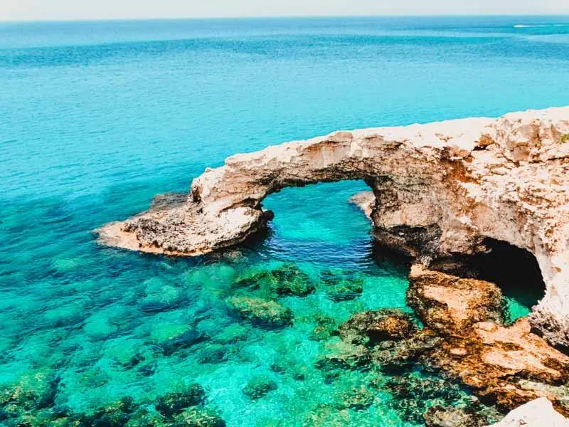 Die felsige Küste Zyperns am Mittelmeer unter blauem Himmel – ein idealer Reisetipp für Badeurlauber im Juli.