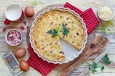 Die fertig gebackene Quiche Lorraine wird aus dem Ofen genommen