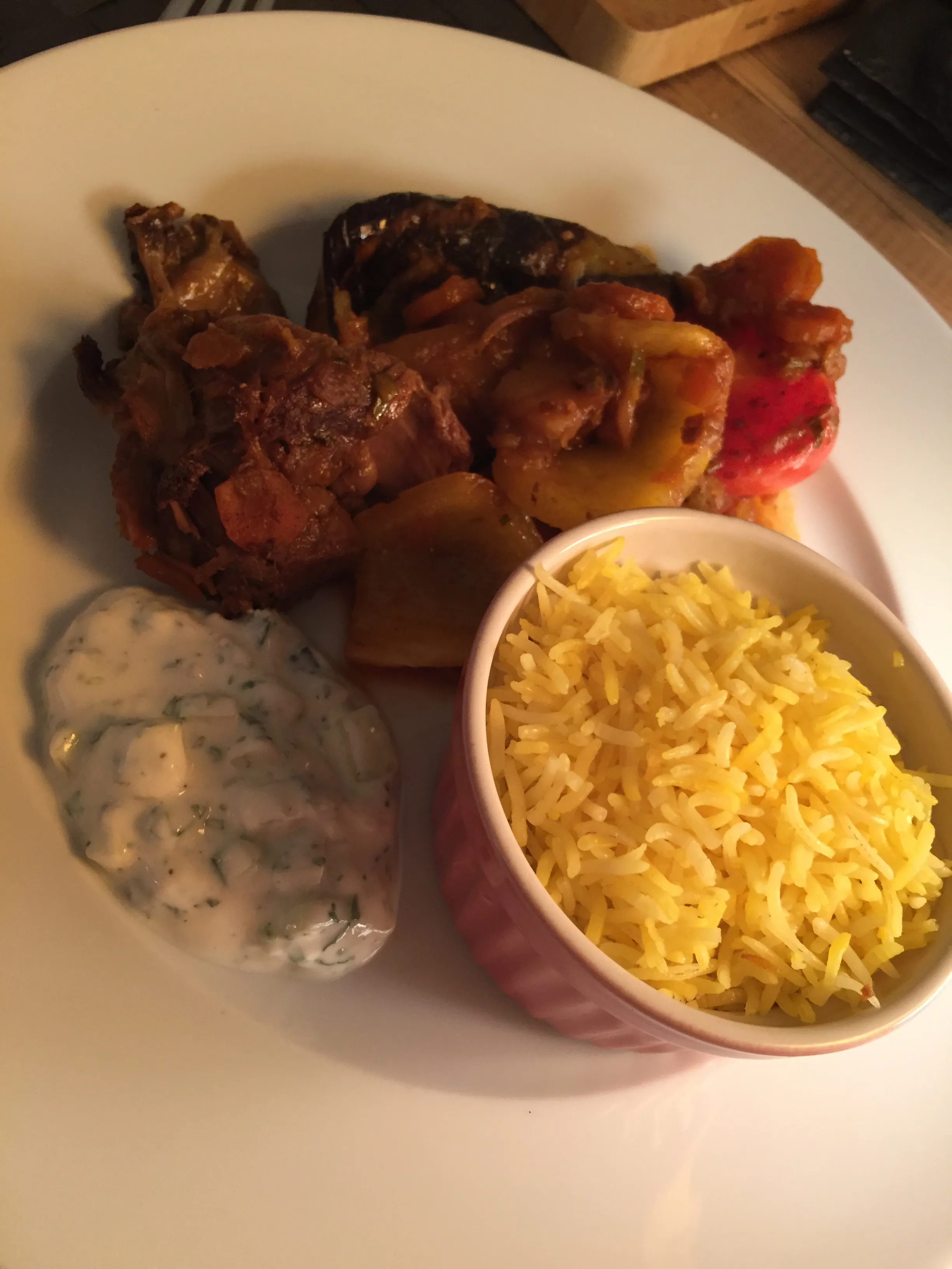 Die fertig geschmorte Lammhaxe mit aromatischem Safranreis und Gemüse serviert.