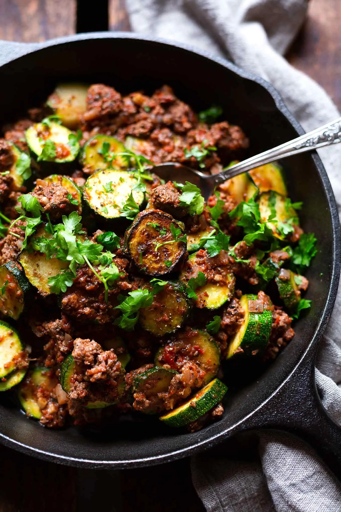 Die fertige Low-Carb-Zucchini-Hackfleisch-Pfanne in einer schwarzen Pfanne, garniert mit glatter Petersilie. Die frische Petersilie sorgt für einen tollen Geschmack.
