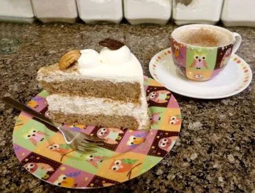 Die fertige Nuss-Sahne-Torte, reichlich mit Sahnetupfen und Nüssen dekoriert