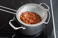 Die fertige Rouladensoße wird durch ein Sieb passiert und mit eiskalter Butter montiert, für eine seidige Textur und reichen Geschmack.