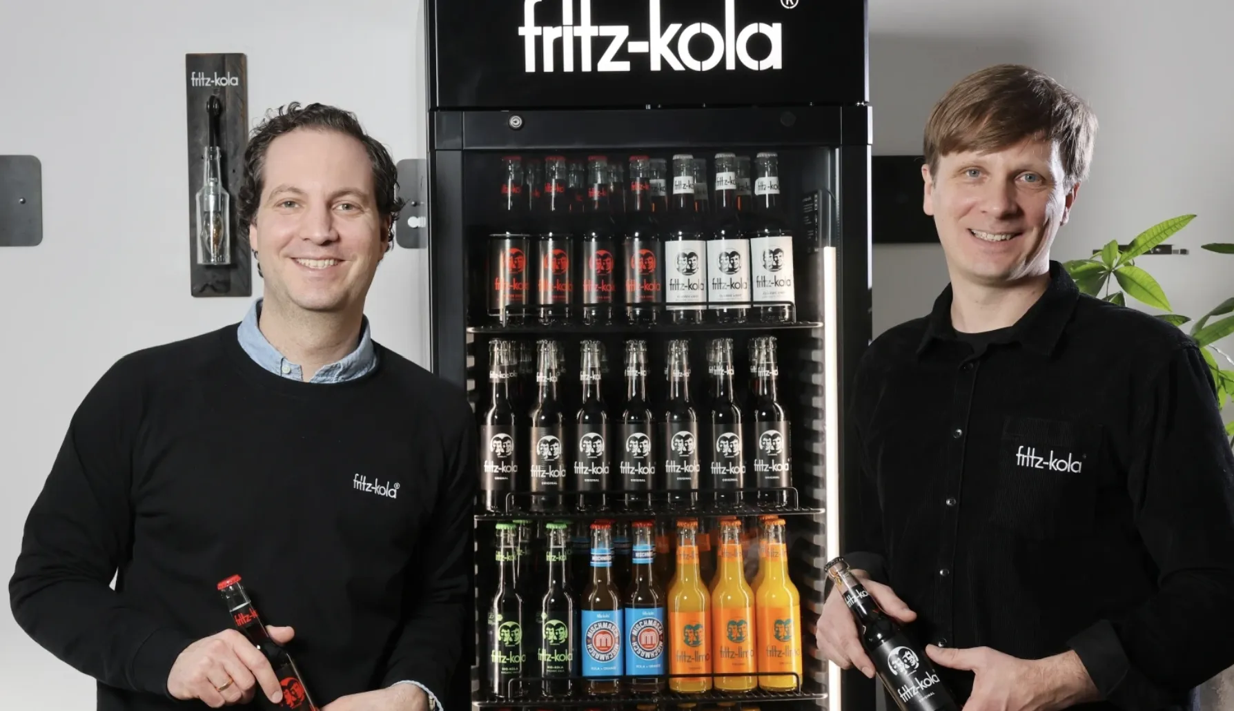 Die Fritz-Kola Flasche mit den Gesichtern der Gründer Lorenz Hampl und Mirco Wolf Wiegert, symbolisch für die authentische Hamburger Marke.
