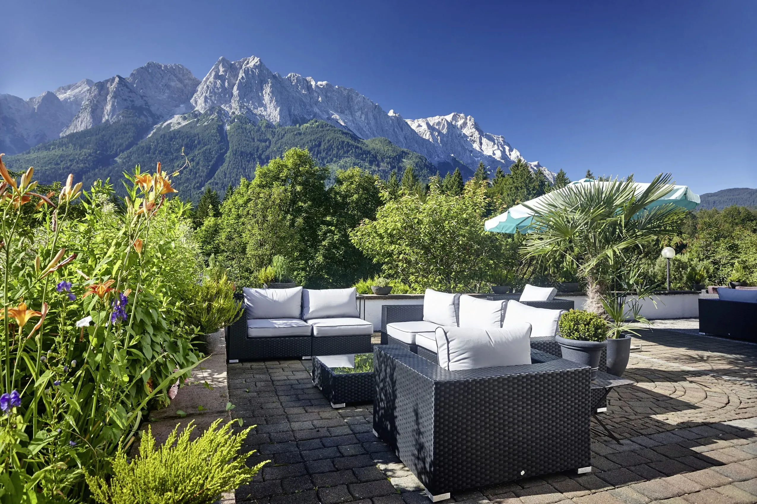 Die stilvolle Terrasse des Romantik Alpenhotel Waxenstein mit Lounge-Möbeln und weitreichendem Blick auf die Berge, wo auch Hunde willkommen sind.